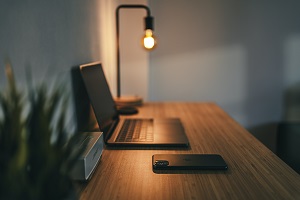 Picture of open laptop on desk with edison light and cell phone