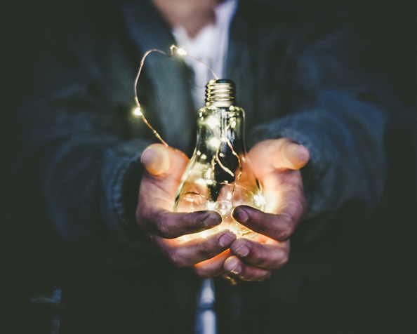 light bulb filled with fairy lights being held in hands